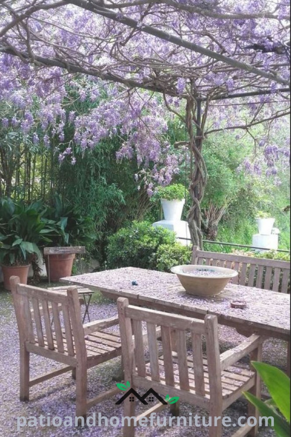 Wooden table under a tree filled with purple flowers, creating a cozy garden atmosphere perfect for entertaining, with decor ideas that inspire natural beauty, captured by wellnesswink.com.