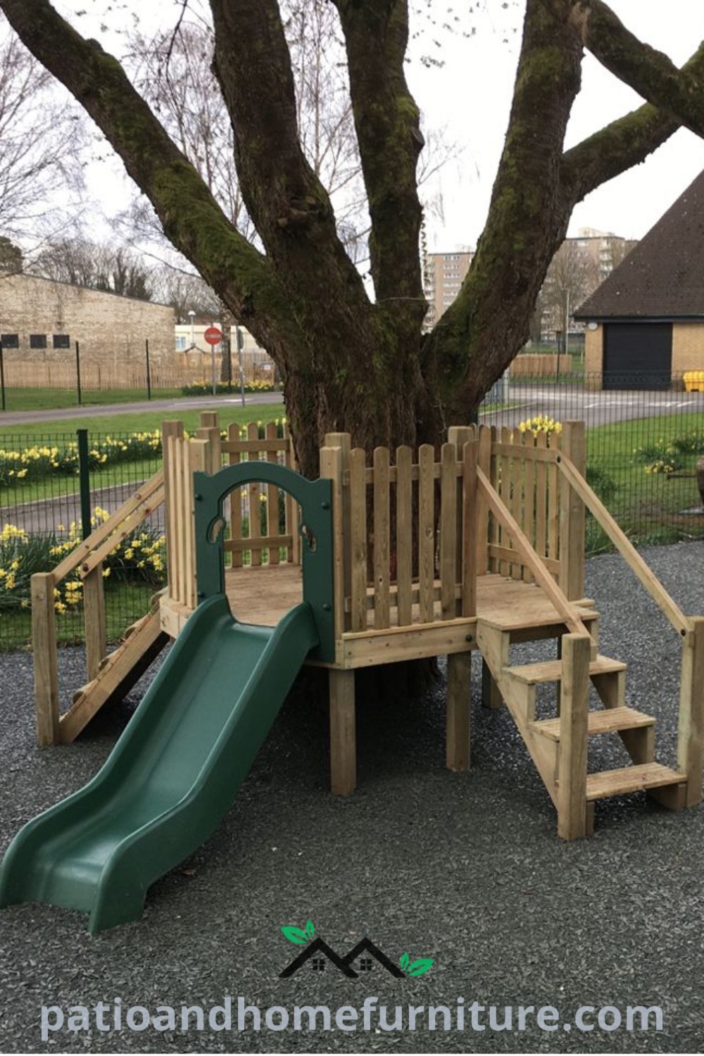 Wooden play set with a green slide next to a large tree in a park, creating a cozy play area for toddlers and kids, capturing the essence of outdoor fun and nature, as featured on wellnesswink.com.