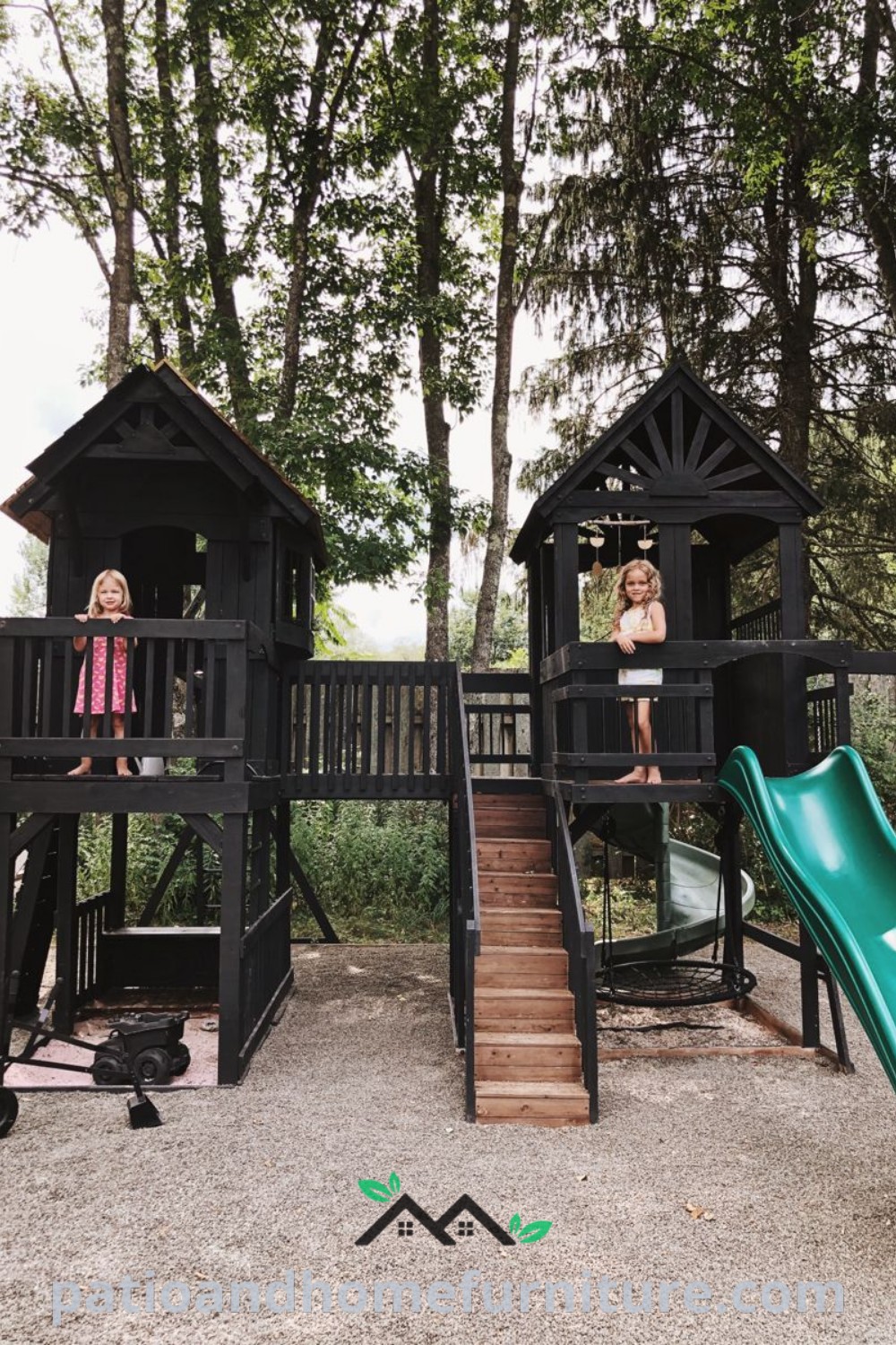 Two girls on a modern black play structure with a slide, enjoying outdoor playtime in a stylish backyard setting, showcasing unique design ideas for cozy outdoor spaces at wellnesswink.com.