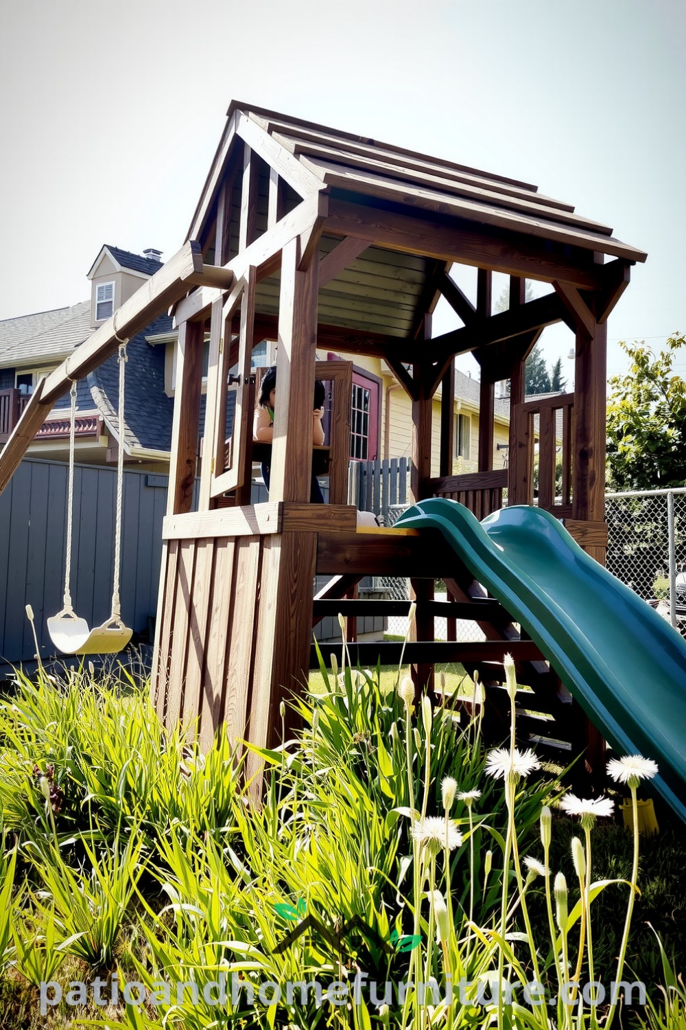 Classic wooden playset in a sun-kissed backyard with swings and a slide, surrounded by tall grass and dandelions, evoking cheerful outdoor fun and adventure, perfect for inspiring cozy home designs and decor ideas from fireplacesandwoodstoves.com.