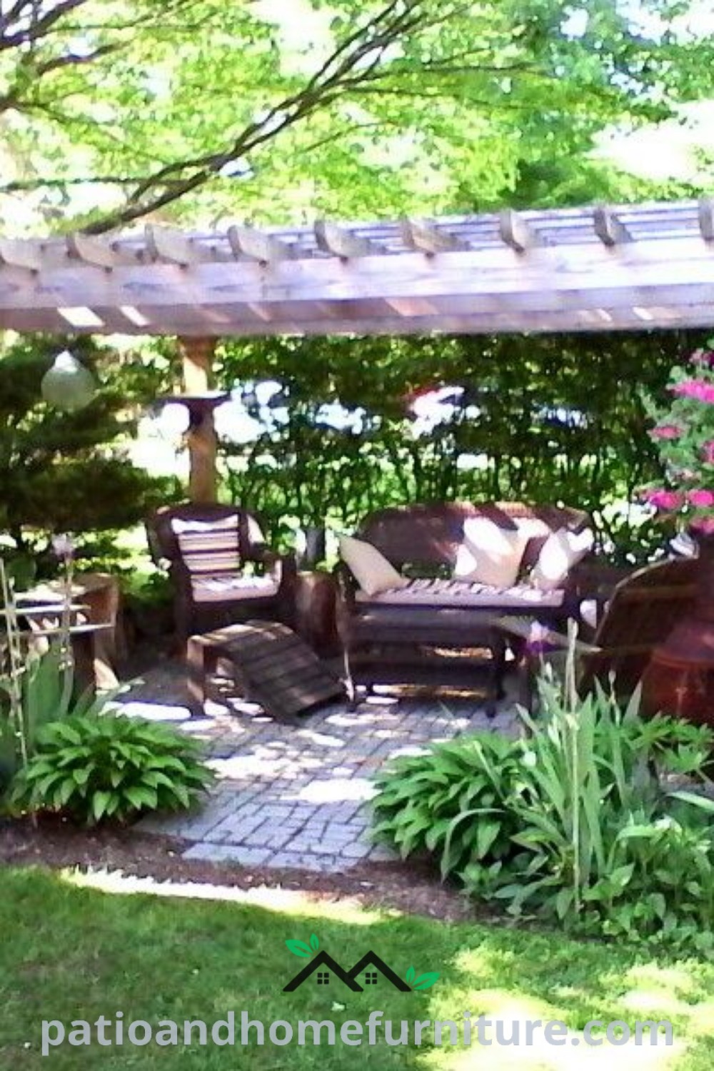 Patio area with chairs and tables surrounded by colorful flower beds, next to a pergola, creating a cozy outdoor oasis perfect for gatherings, with decor ideas that inspire a beautiful backyard space, featured on wellnesswink.com.