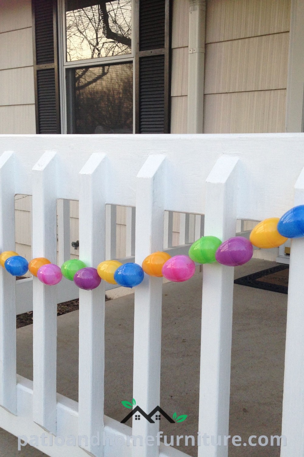 A cozy front porch with a white picket fence decorated with colorful plastic balls and streamers, complemented by an inviting atmosphere perfect for springtime decorating ideas, found at wellnesswink.com.