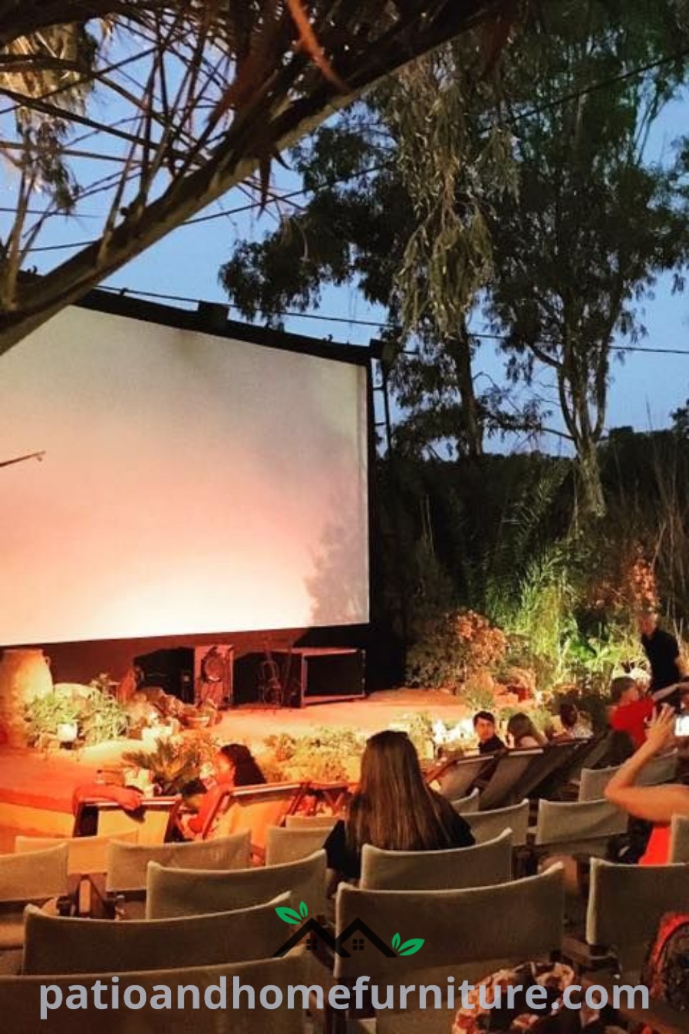 Outdoor movie night setting with people sitting in chairs watching a large screen, surrounded by string lights and a cozy atmosphere, perfect for gatherings and inspired outdoor decor ideas. Visit wellnesswink.com for unique ideas for your home.