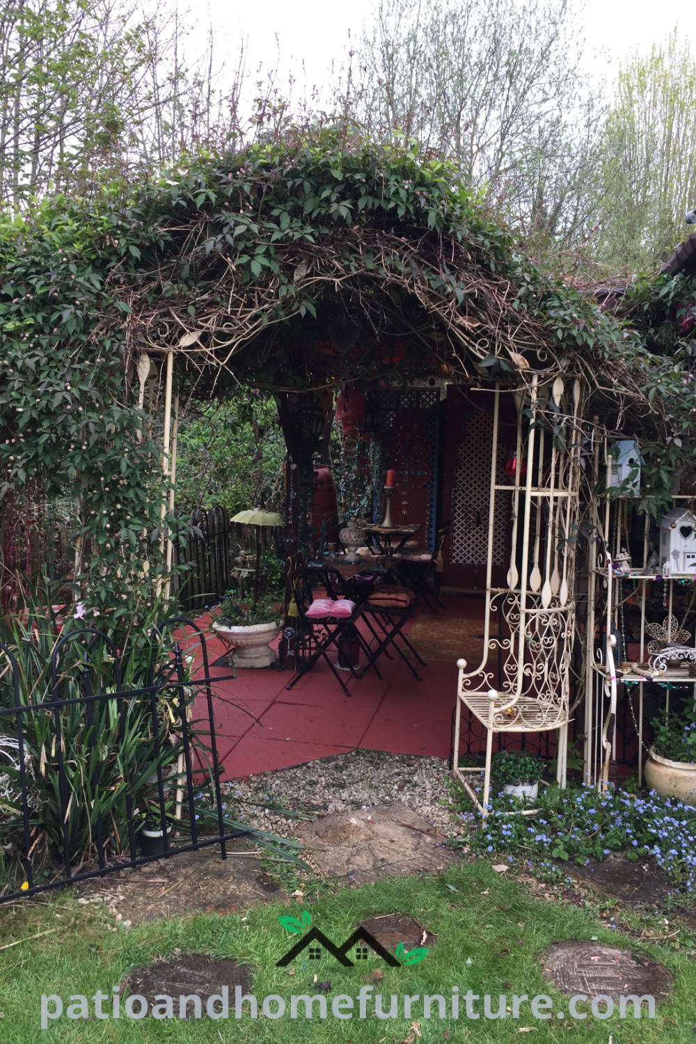 A gazebo covered in vines and flowers beside a table and chairs, creating a cozy outdoor retreat for gatherings and relaxation, featuring inspiring garden decor ideas suitable for a backyard or courtyard oasis, wellnesswink.com.