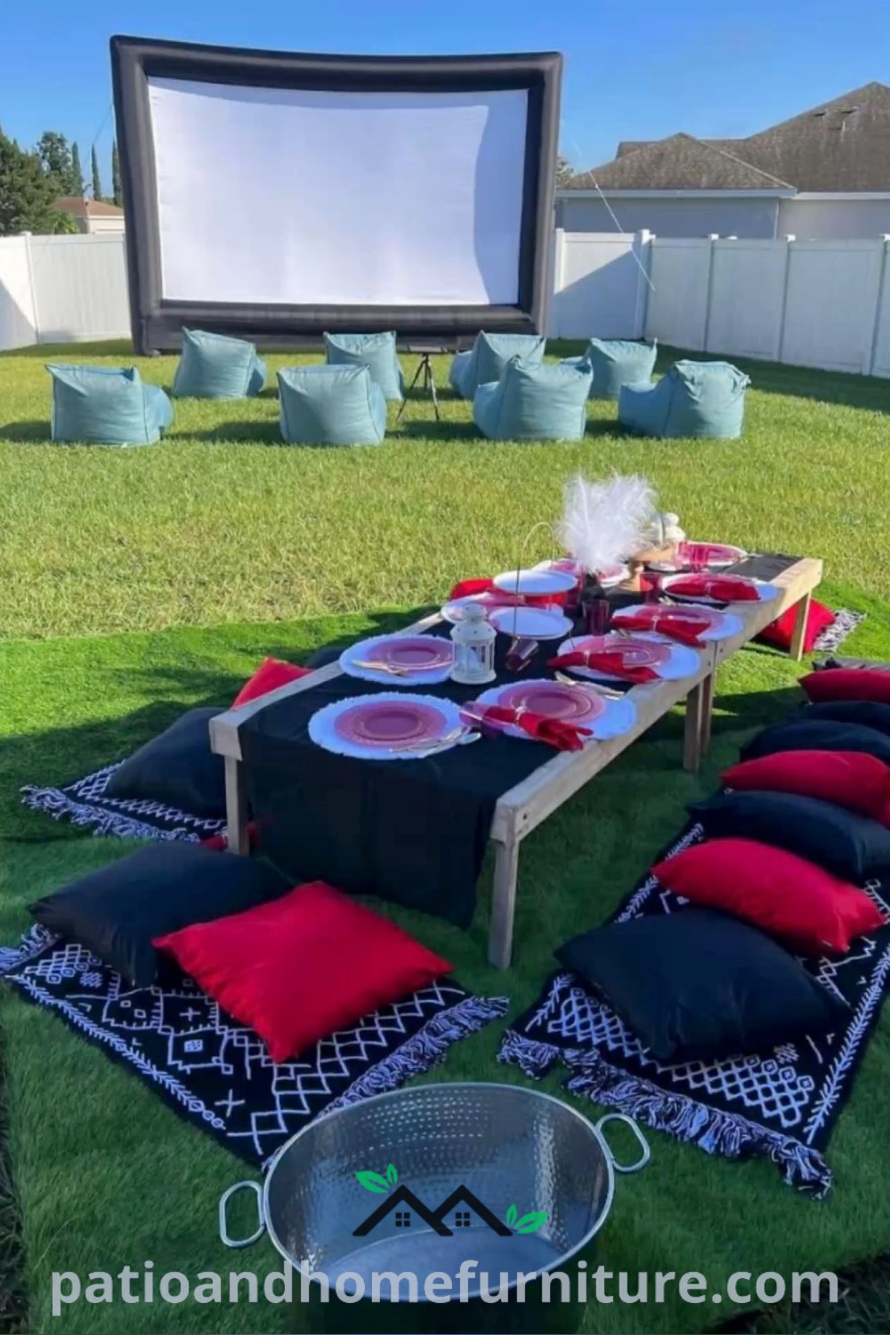 Outdoor movie party scene with black and red pillows on grass in front of a screen, featuring cozy ideas and decor inspirations for a fun and inviting backyard cinema experience at wellnesswink.com.