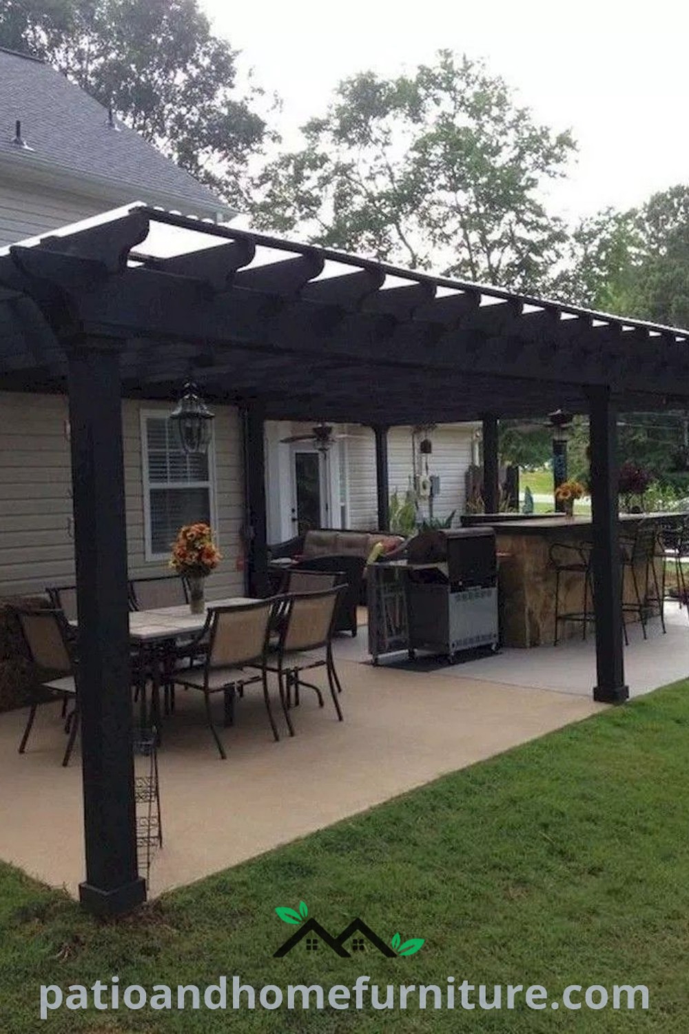Patio with black plastic furniture next to a white house and outdoor kitchen, showcasing cozy decor ideas and inviting design inspirations for your home at wellnesswink.com.