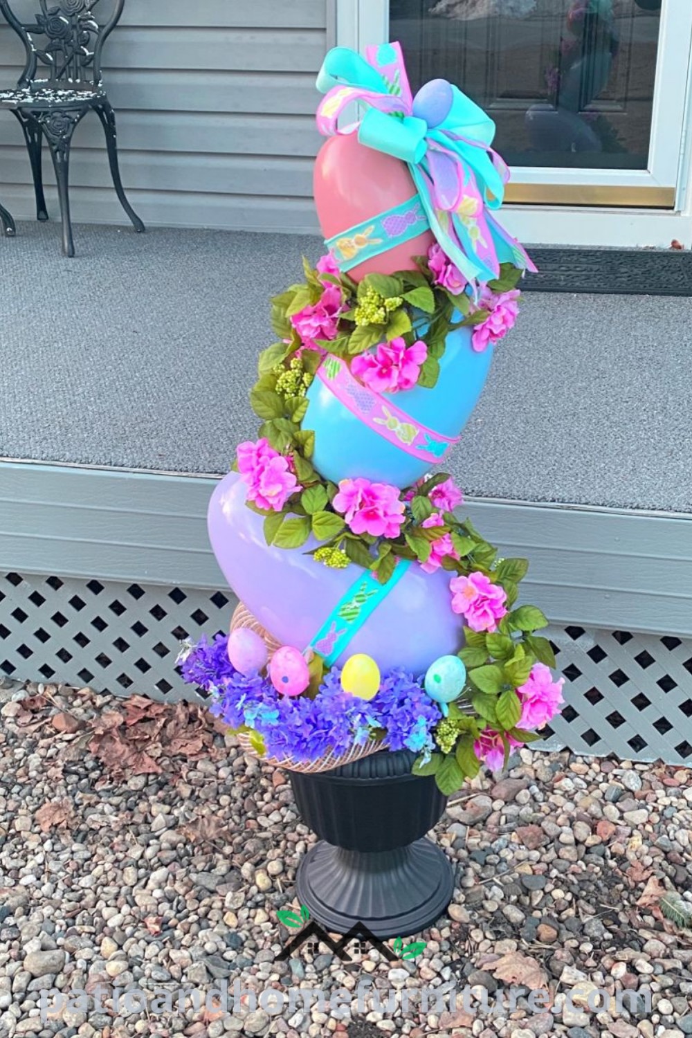 A tall vase filled with colorful flowers placed on a gravel surface next to a door, showcasing charming Easter decor ideas, perfect for creating a cozy and inviting atmosphere at home; visit wellnesswink.com for unique design inspirations.