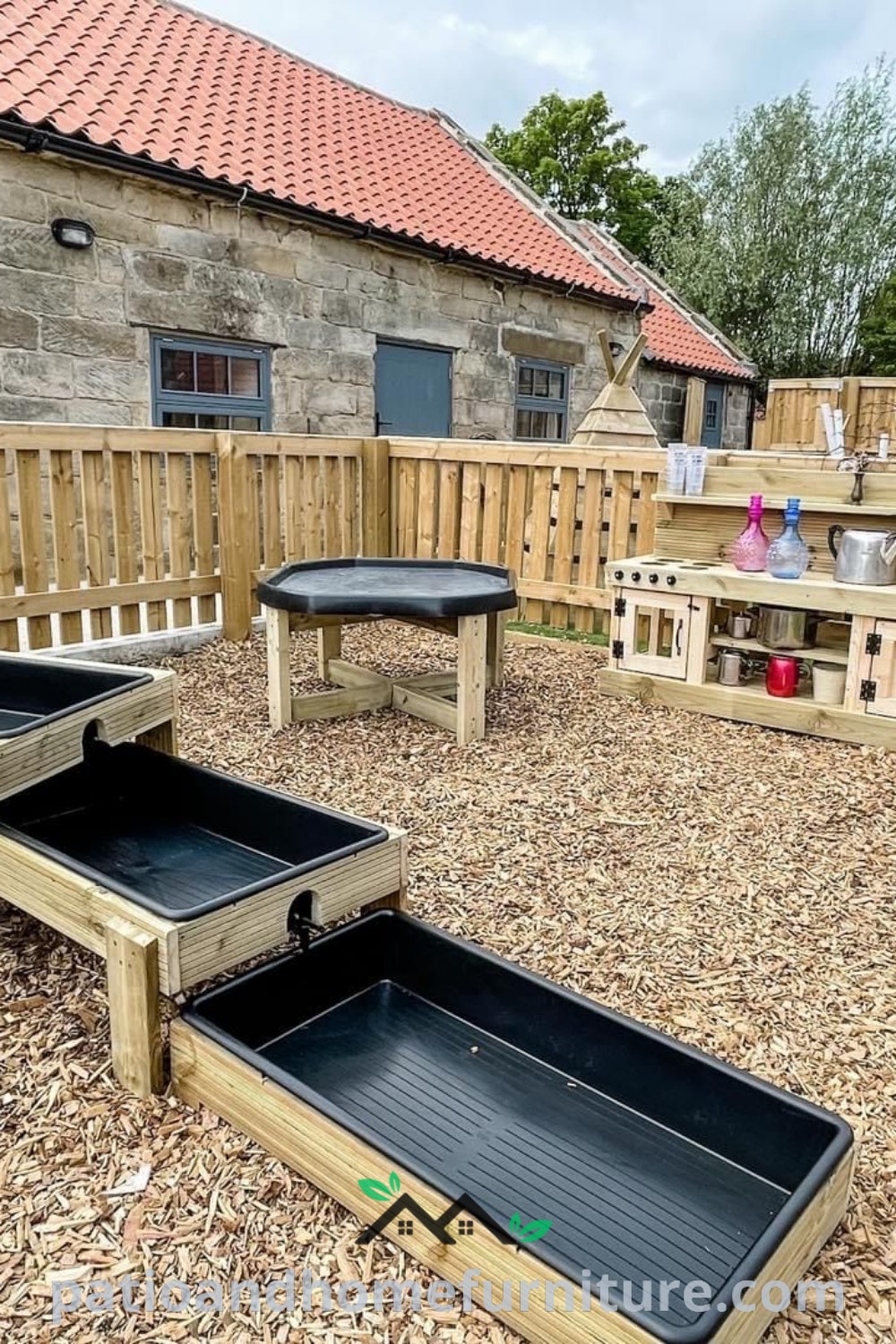 Wooden deck with benches and tables in a graveled area next to a stone building, showcasing cozy ideas for outdoor play spaces, perfect for kids and toddlers, featured on wellnesswink.com.