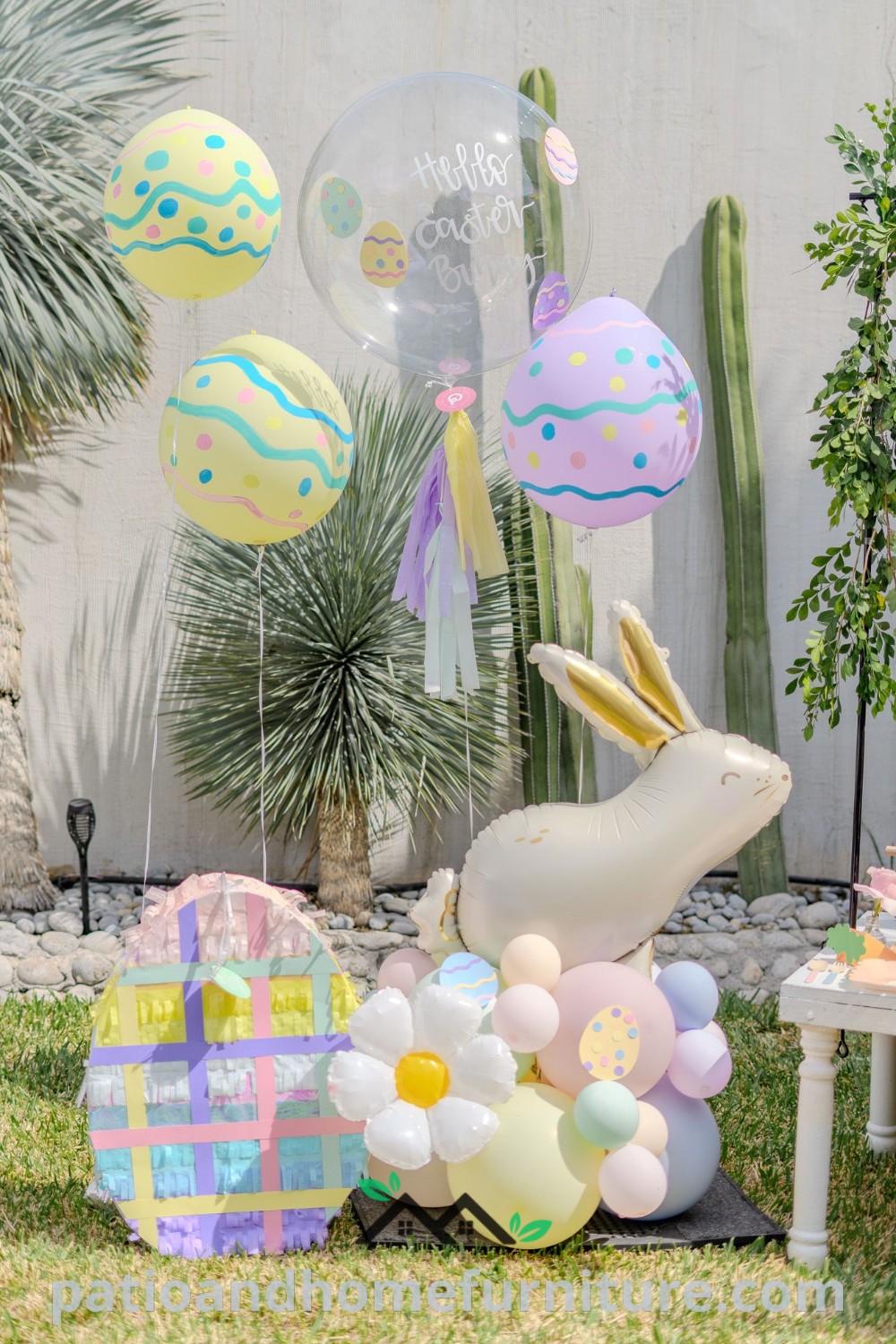 Outdoor Easter party setup featuring colorful balloons, festive decorations, cactus trees, palm trees, and rocks in front of a cozy home, offering unique decor ideas and inspirations for cheerful celebrations. Visit wellnesswink.com for more design ideas.