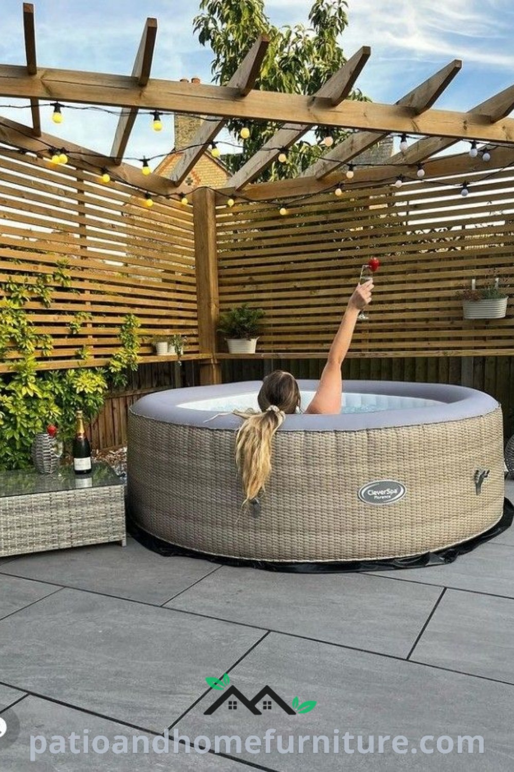 Woman relaxing in an outdoor hot tub with arms up and legs crossed, surrounded by a beautifully designed patio featuring lush greenery and cozy decor inspirations, perfect for creating a unique home retreat on wellnesswink.com.