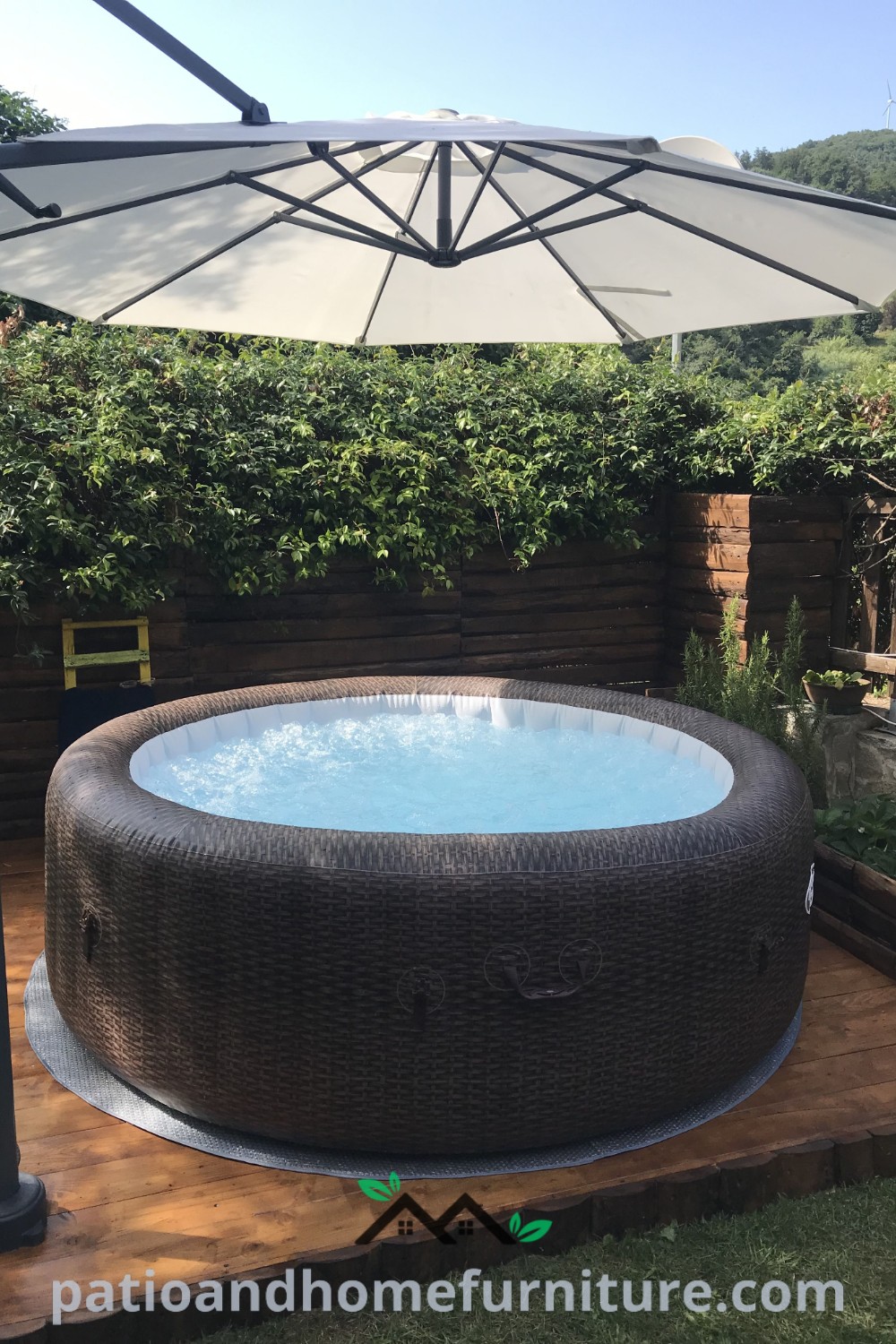Inflatable hot tub on a wooden deck beside a white umbrella, surrounded by a tranquil garden setting, showcasing cozy home design ideas for outdoor relaxation at wellnesswink.com.