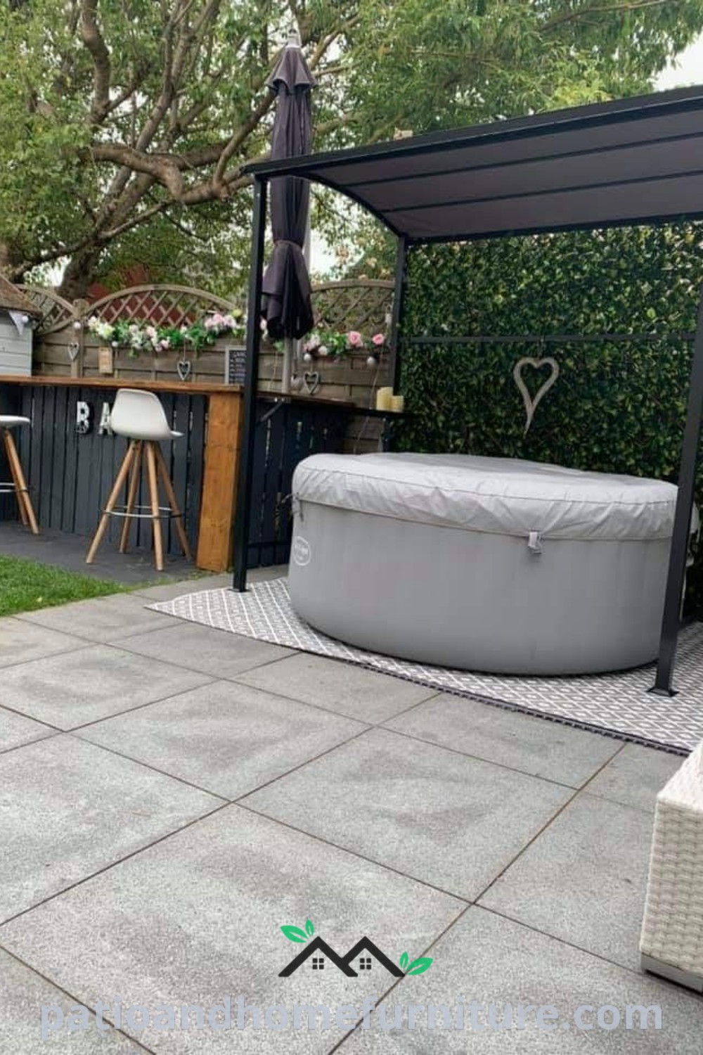 Cozy outdoor patio with a hot tub, table, and lush plants, featuring a pergola and warm string lighting, creating a serene backyard oasis that inspires relaxation and enjoyment, perfect for home decor ideas at wellnesswink.com.