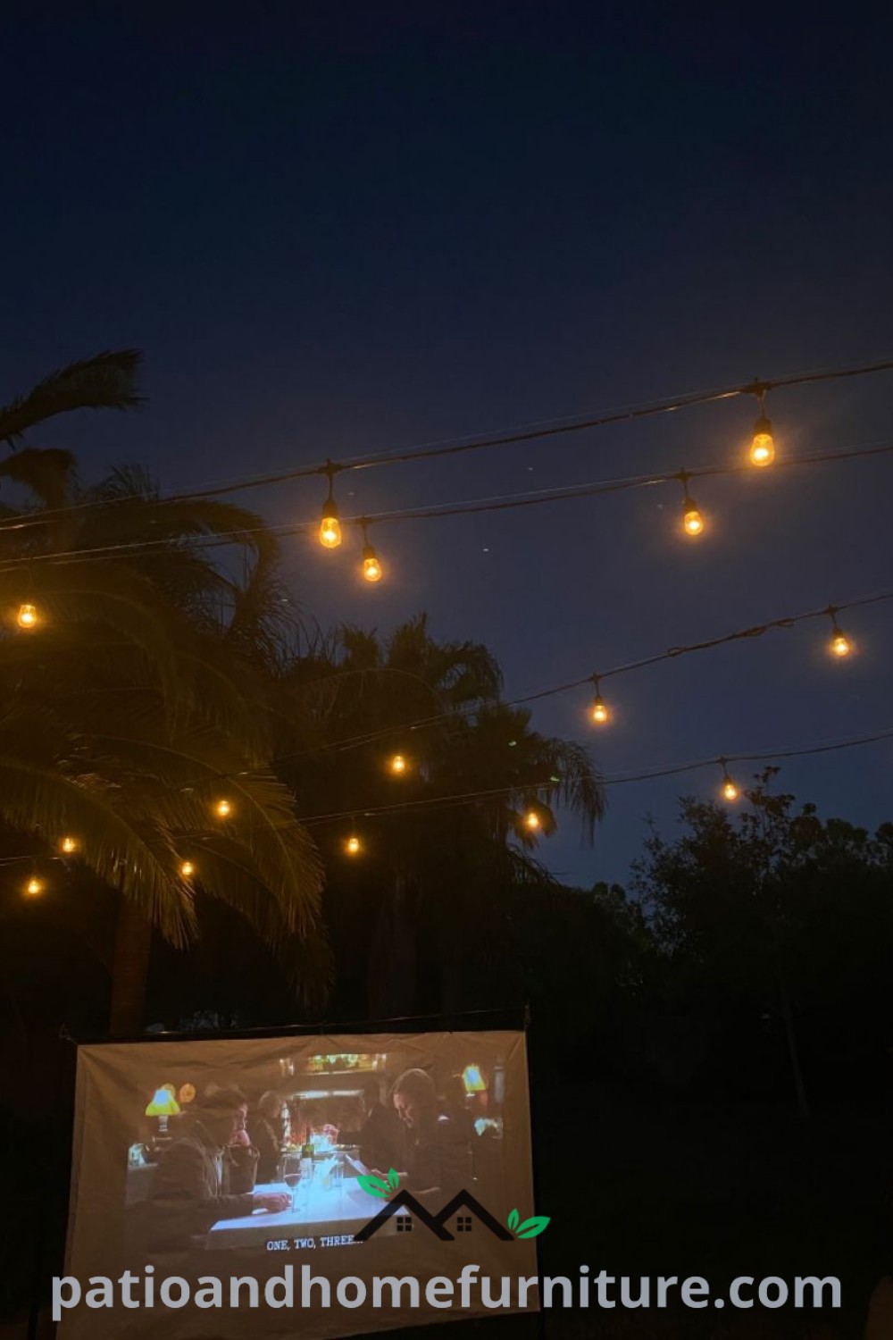 Outdoor movie screen with string lights and palm trees in the background, creating a cozy atmosphere for movie nights, with unique ideas for backyard decor available at wellnesswink.com.
