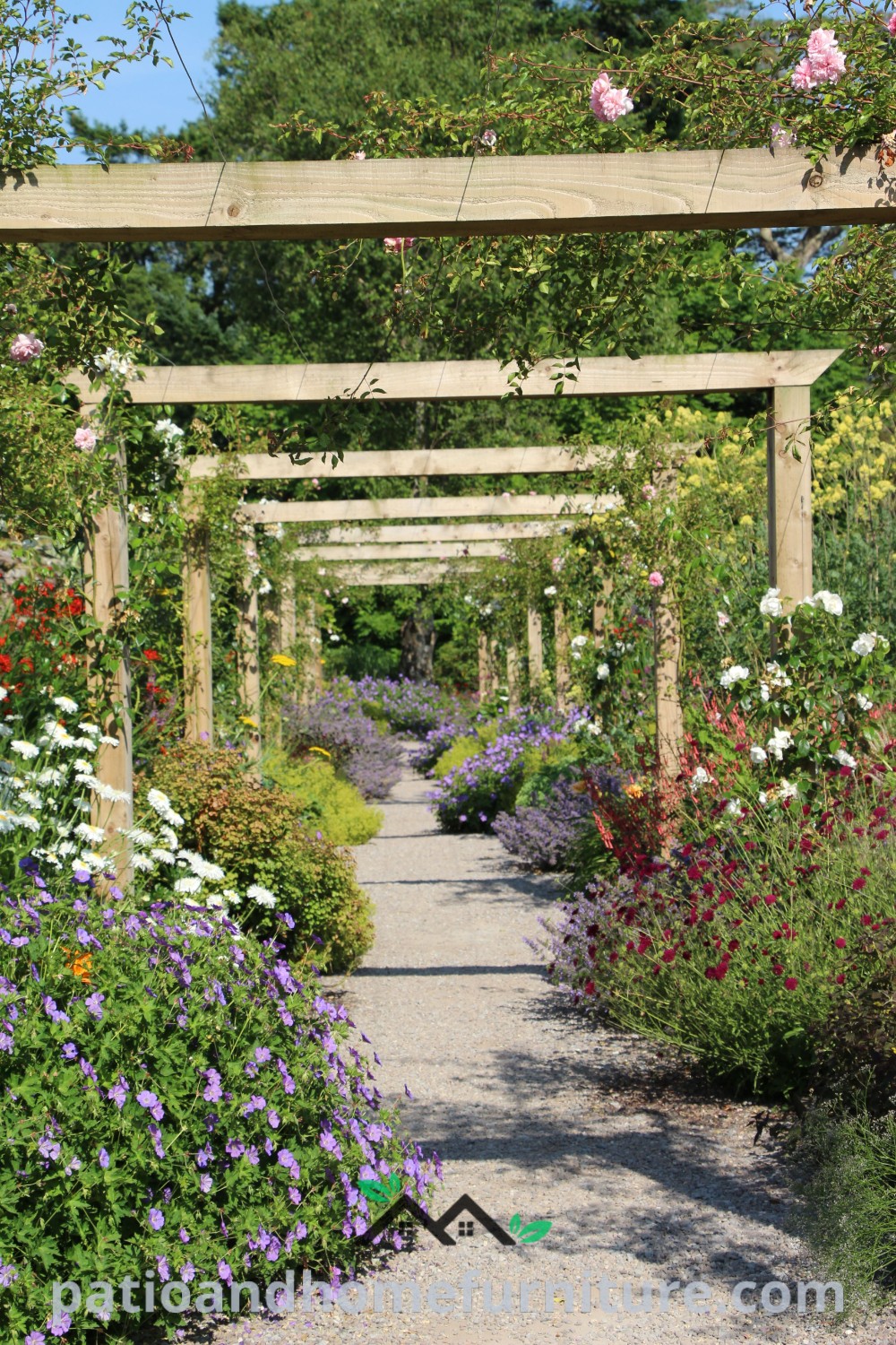 A beautiful garden filled with colorful flowers and a lush green forest in the background, featuring a stunning arch decorated with purple and white flowers, showcasing cozy design ideas and inspirations for creating a floral paradise for your home on wellnesswink.com.