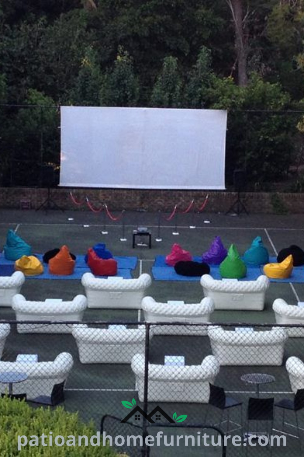 Outdoor movie theater featuring white chairs and a large screen surrounded by lush trees, offering cozy ideas for backyard cinema, perfect for a memorable movie night experience, inspired by wellnesswink.com.
