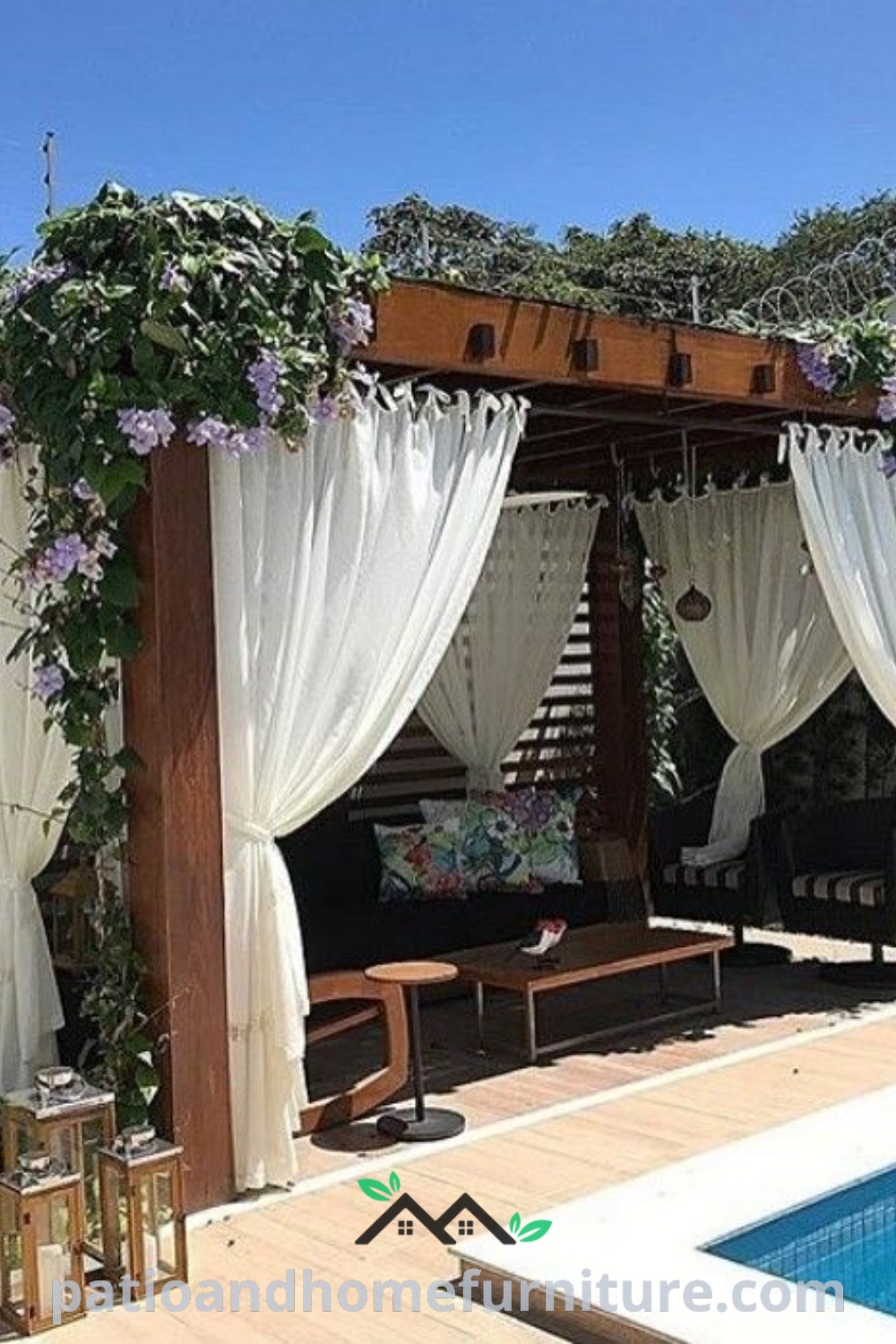 Cozy outdoor living area beside a swimming pool with white drapes and colorful flowers, showcasing unique decor ideas for a welcoming backyard oasis, featured on wellnesswink.com.