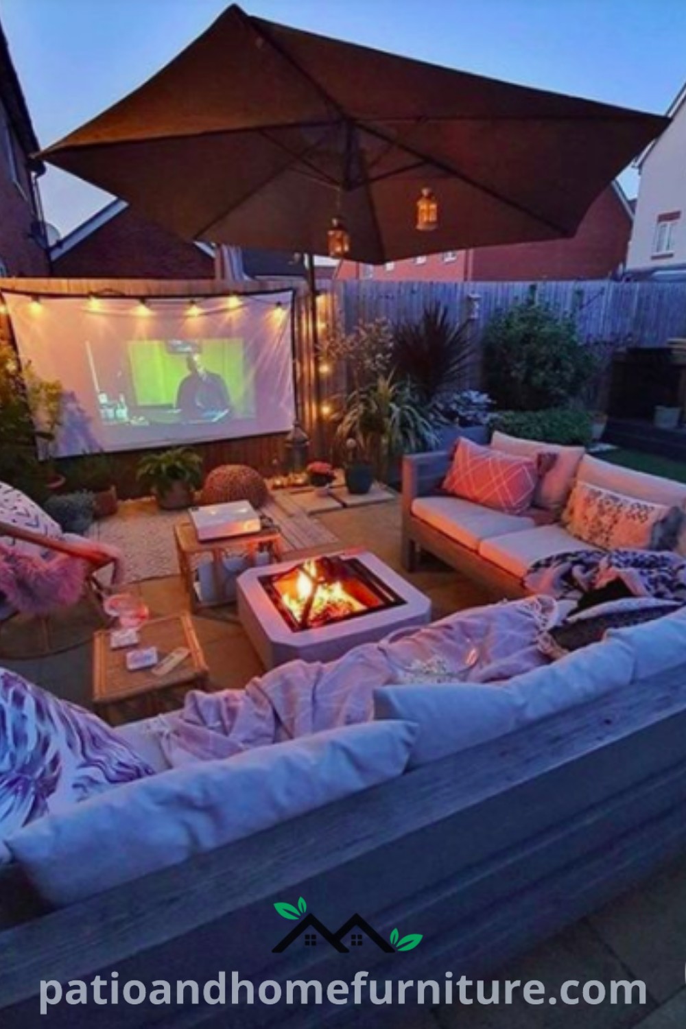 Cozy outdoor living room featuring couches around a fire pit, designed for backyard movie nights with a projector and twinkling lights, offering inspiration for creating a comfortable and inviting outdoor space, presented by wellnesswink.com.