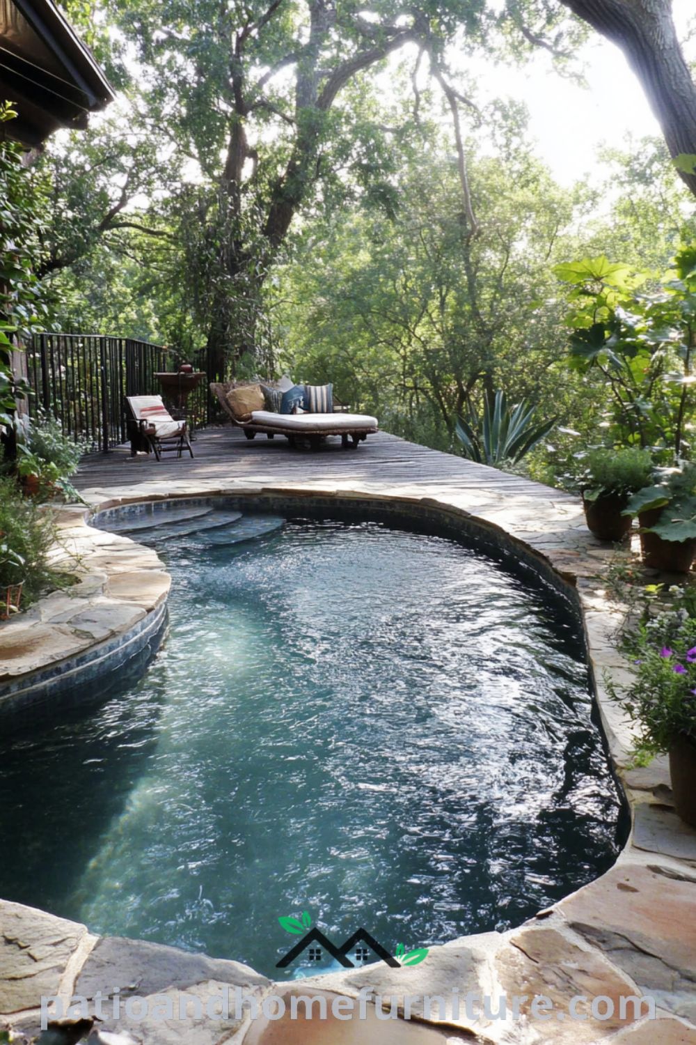 Backyard pool surrounded by irregular stone paving, lush greenery, and wildflowers, with a rustic wooden deck ideal for sunbathing, creating a cozy retreat for summer relaxation, featured on fireplacesandwoodstoves.com.