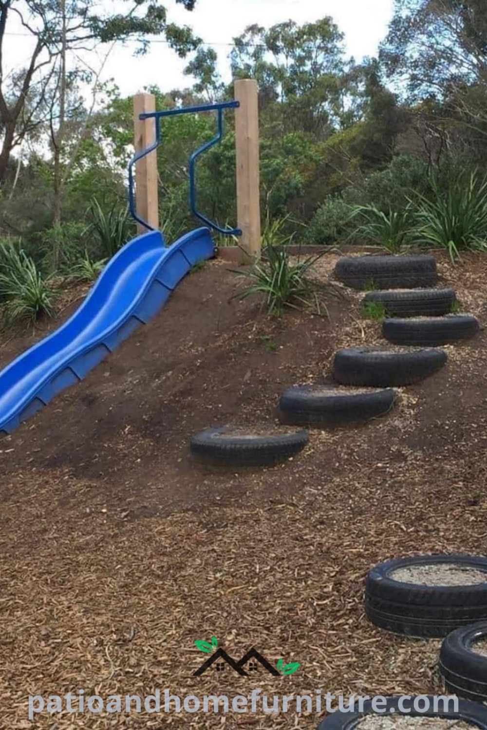 Blue slide and tires in the dirt create a fun outdoor play area for kids, surrounded by natural elements, offering inspiring and cozy decor ideas for families looking to enhance their backyard, featured on wellnesswink.com.