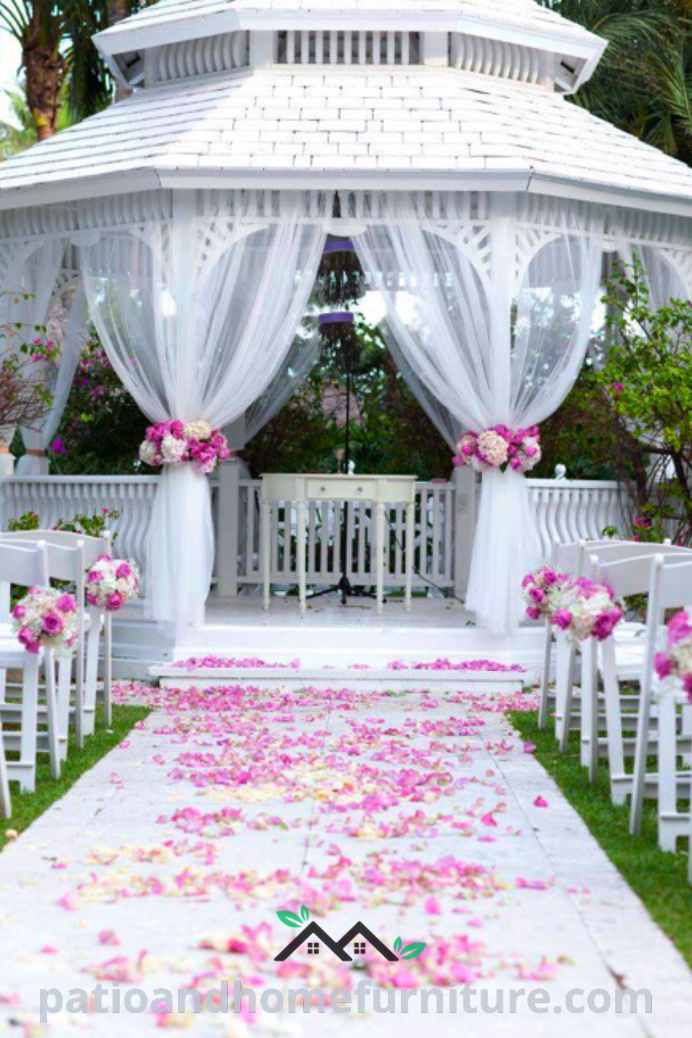 White gazebo surrounded by pink flowers and petals on the grass, setting a romantic scene for a wedding ceremony; discover cozy ideas for outdoor decor at wellnesswink.com.